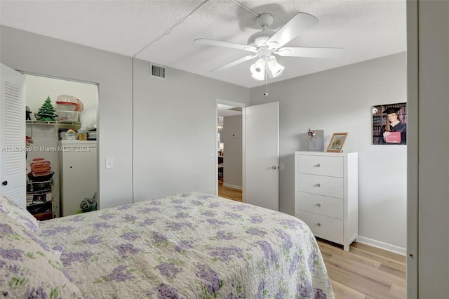 bedroom with light hardwood / wood-style flooring, a textured ceiling, ceiling fan, and a closet