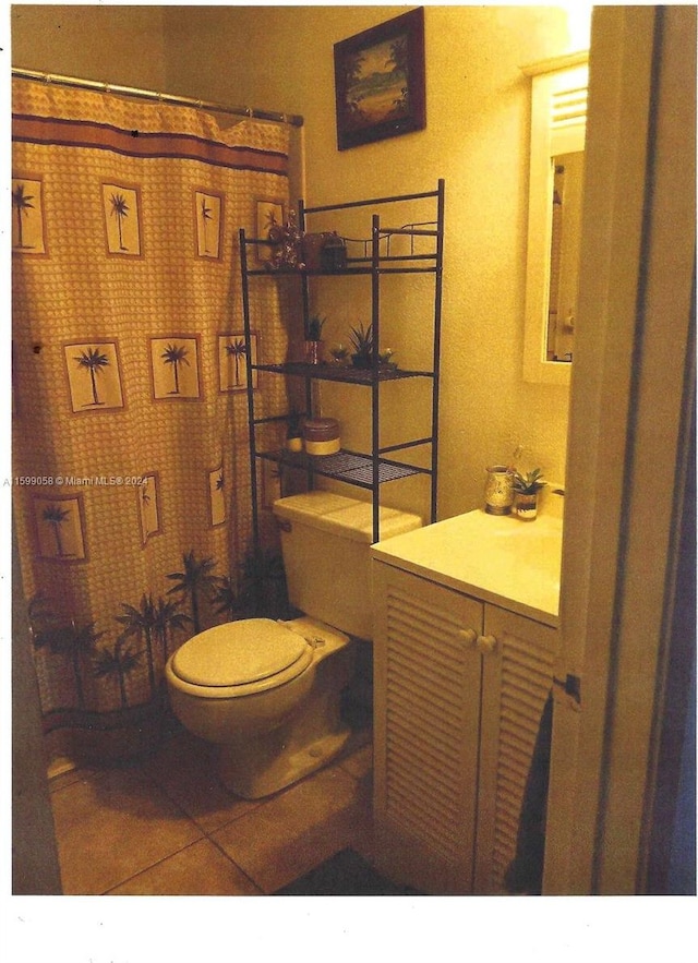 bathroom with toilet, vanity, and tile patterned floors