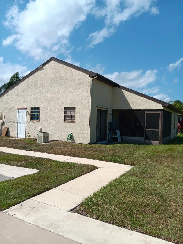 view of side of property with cooling unit and a lawn