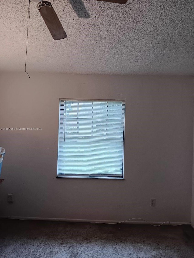 unfurnished room with ceiling fan, a textured ceiling, and carpet floors