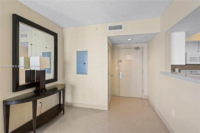 hall with electric panel, visible vents, a textured ceiling, and light tile patterned flooring