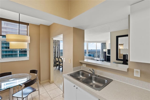 kitchen featuring light tile patterned floors, white cabinetry, light countertops, and a sink