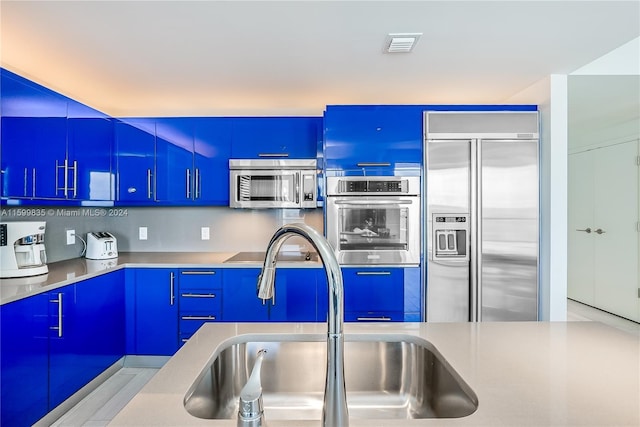 kitchen with blue cabinetry, sink, and stainless steel appliances