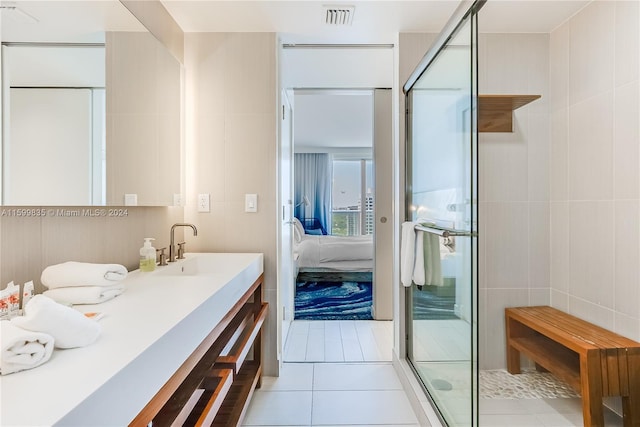 bathroom with vanity, tile patterned floors, an enclosed shower, and tile walls