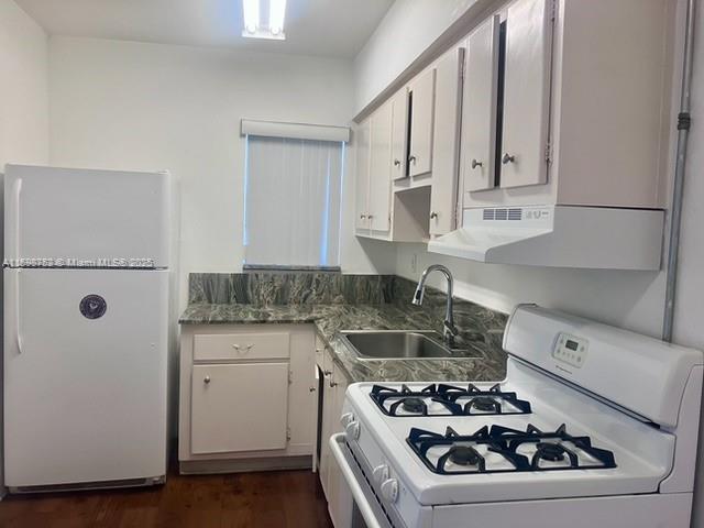 kitchen with white cabinets, dark wood-type flooring, sink, and white appliances