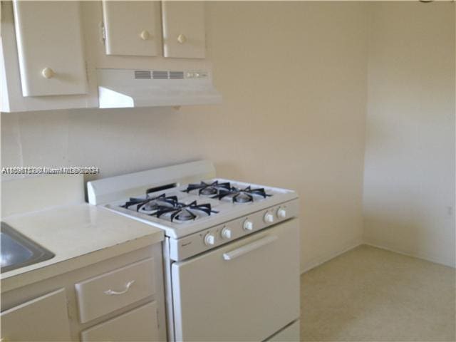 kitchen with white cabinets, white range with gas stovetop, sink, and extractor fan