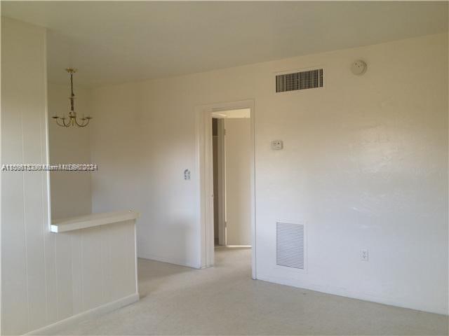 carpeted empty room with a notable chandelier