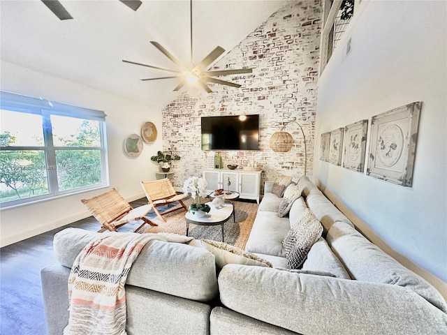 living room with high vaulted ceiling, hardwood / wood-style flooring, brick wall, and ceiling fan