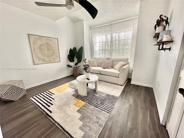 living room featuring a textured ceiling, dark wood-type flooring, and ceiling fan