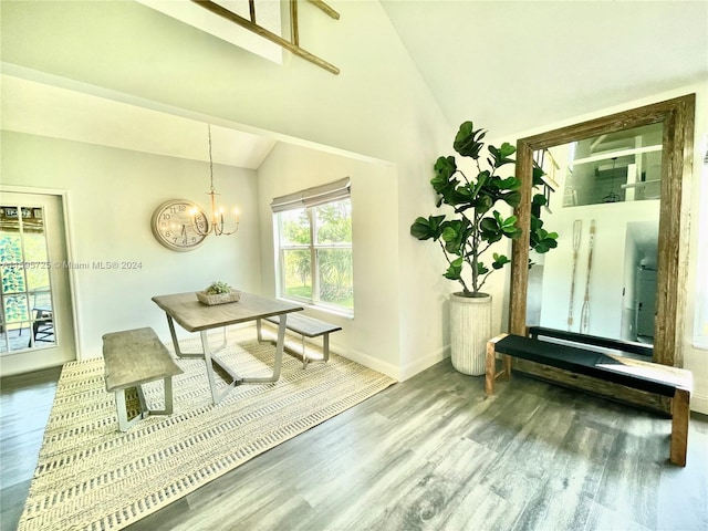 dining space with high vaulted ceiling, an inviting chandelier, and hardwood / wood-style flooring