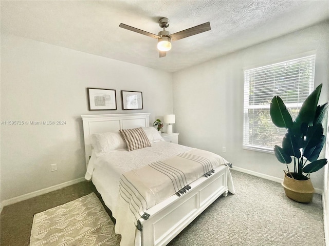 carpeted bedroom featuring ceiling fan, a textured ceiling, and multiple windows