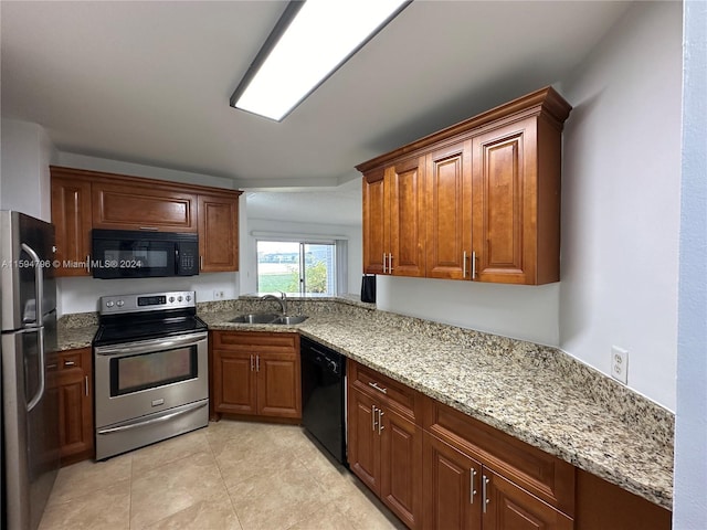 kitchen featuring light stone counters, light tile patterned flooring, sink, and black appliances