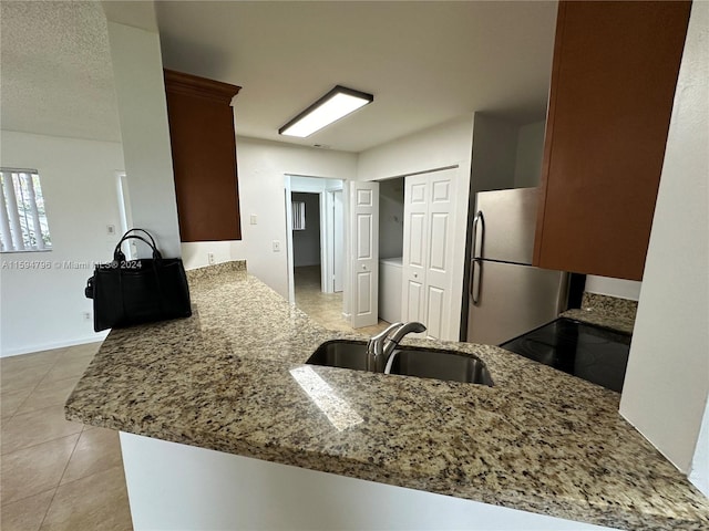 kitchen featuring stainless steel fridge, range, kitchen peninsula, and sink