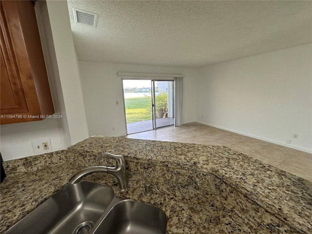 kitchen featuring sink, a textured ceiling, and dark stone countertops