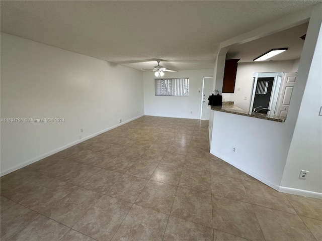 unfurnished living room featuring ceiling fan and a textured ceiling