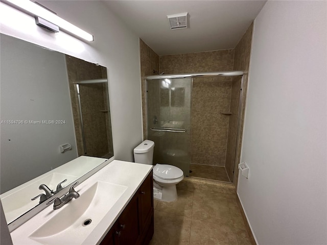 bathroom featuring tile patterned flooring, vanity, an enclosed shower, and toilet