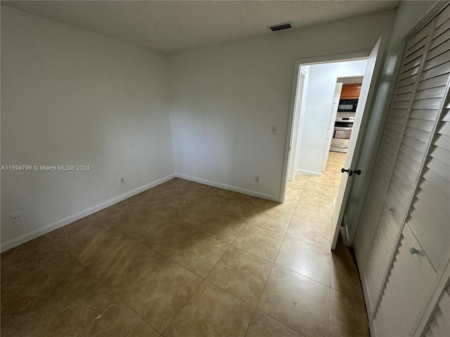 tiled spare room featuring a textured ceiling