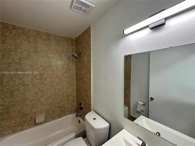 full bathroom with tiled shower / bath, vanity, and toilet