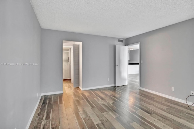 empty room with a textured ceiling and wood-type flooring