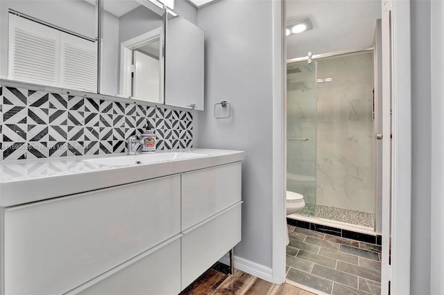 bathroom featuring vanity with extensive cabinet space, toilet, hardwood / wood-style floors, and a shower with door