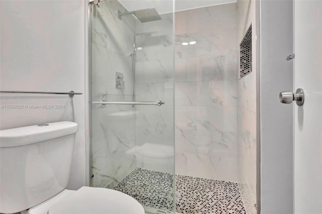 bathroom with a shower with shower door and toilet