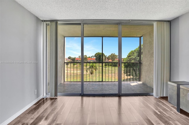 unfurnished room featuring floor to ceiling windows, a textured ceiling, and hardwood / wood-style floors