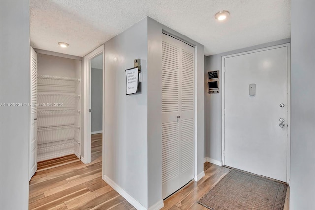 corridor featuring light hardwood / wood-style flooring and a textured ceiling