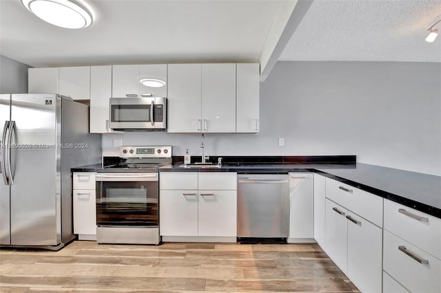 kitchen with stainless steel appliances, white cabinets, and light wood-type flooring