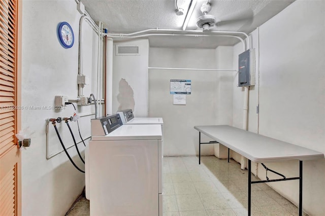 clothes washing area with independent washer and dryer, a textured ceiling, light tile floors, and hookup for a washing machine