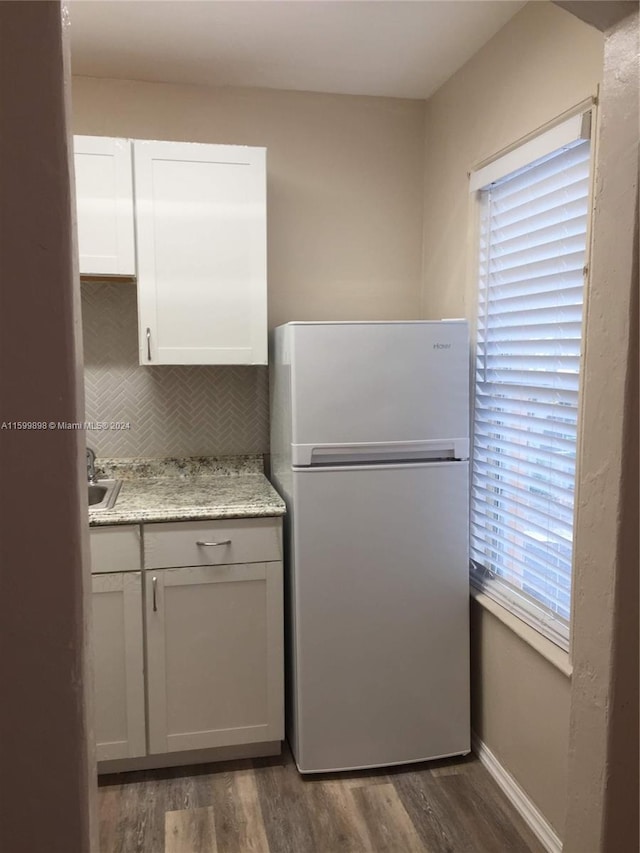 kitchen featuring backsplash, dark wood-type flooring, white cabinets, white refrigerator, and light stone countertops