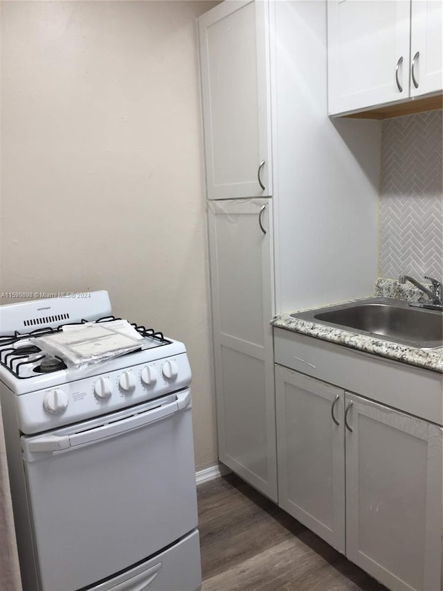 kitchen featuring white cabinets, sink, white gas range oven, tasteful backsplash, and dark hardwood / wood-style flooring