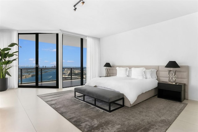 bedroom featuring tile flooring, expansive windows, rail lighting, and access to outside