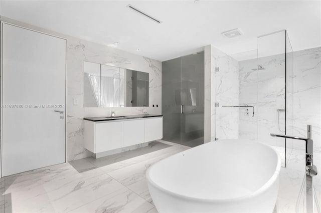 bathroom with tile walls, tile floors, separate shower and tub, and vanity with extensive cabinet space