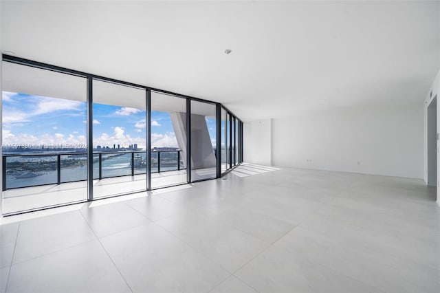 tiled spare room with floor to ceiling windows and a water view