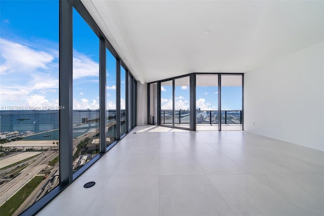 empty room with tile floors and a wall of windows