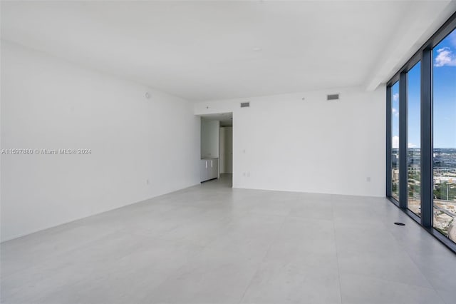 empty room with tile flooring and a wall of windows