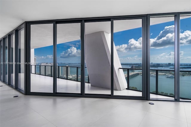 tiled empty room featuring a water view and expansive windows