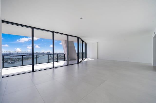 spare room with tile floors, floor to ceiling windows, and a water view