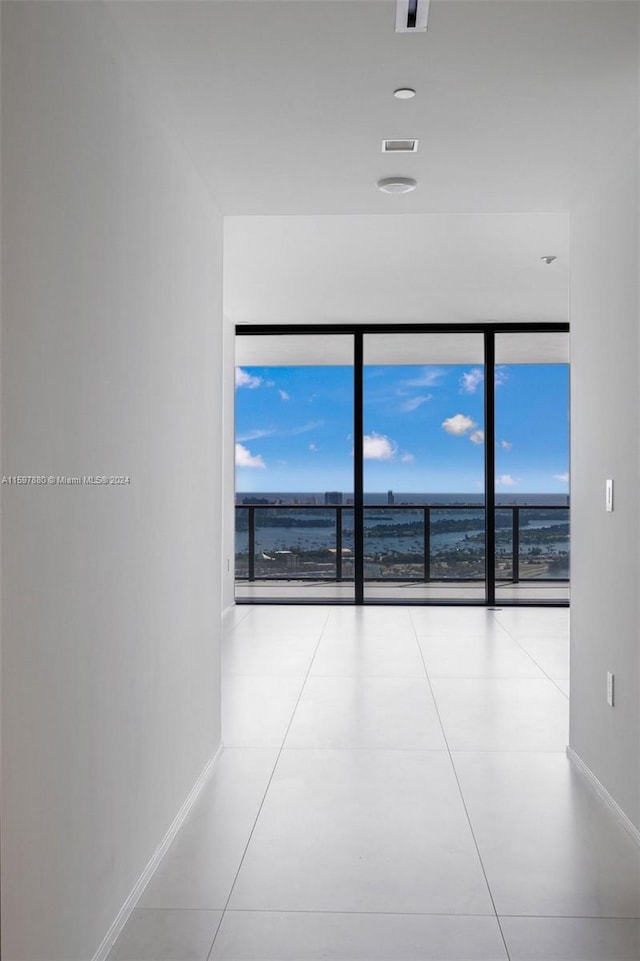 unfurnished room featuring a water view, expansive windows, and light tile floors