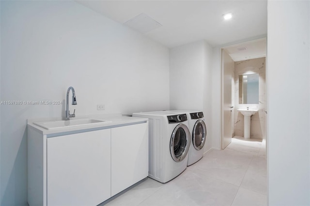 washroom with sink, washing machine and dryer, and light tile floors