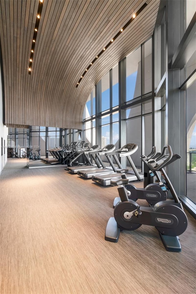 gym with a high ceiling, hardwood / wood-style floors, expansive windows, and wooden ceiling