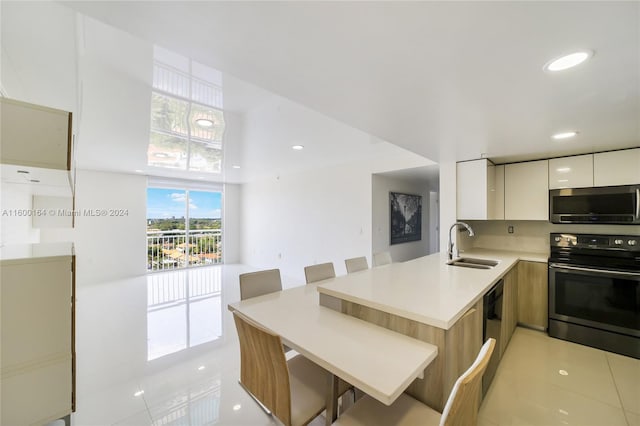 kitchen featuring stainless steel microwave, modern cabinets, electric range, a peninsula, and a sink