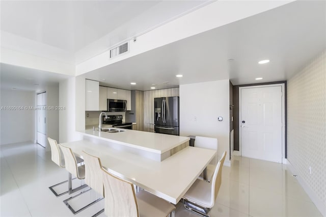 kitchen with kitchen peninsula, stainless steel appliances, light tile patterned flooring, and sink