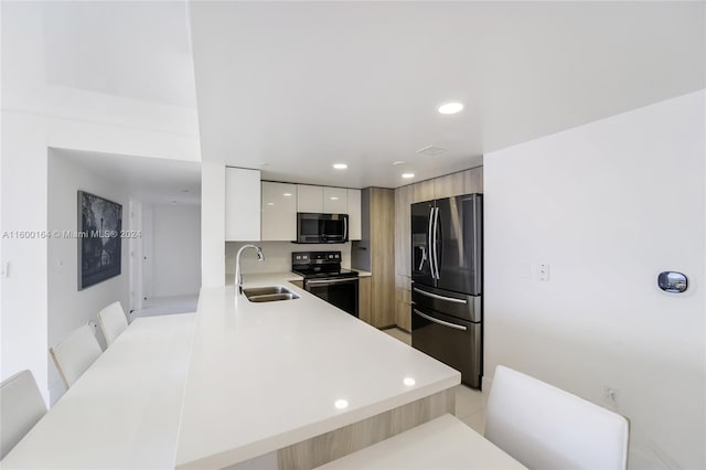 kitchen with a kitchen bar, sink, black fridge, electric range oven, and light tile patterned floors