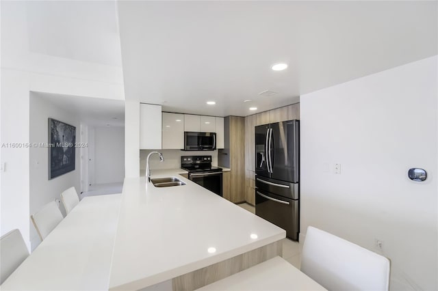 kitchen with appliances with stainless steel finishes, modern cabinets, a sink, light countertops, and a peninsula