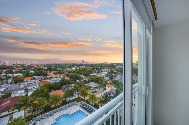 balcony at dusk featuring a community pool