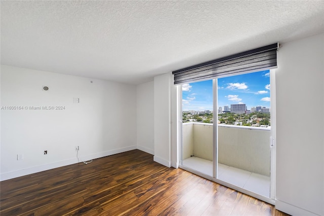 spare room with wood finished floors, a view of city, baseboards, and a textured ceiling