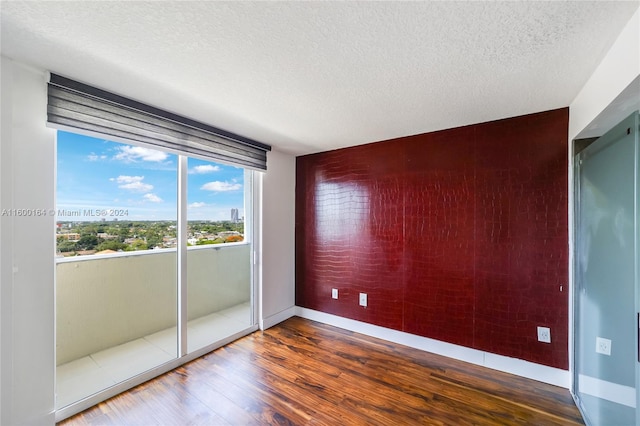 empty room featuring wood finished floors, baseboards, and a textured ceiling