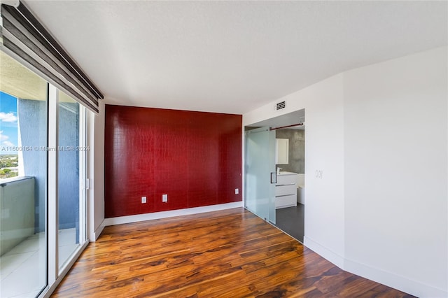spare room with an accent wall, wood finished floors, and baseboards