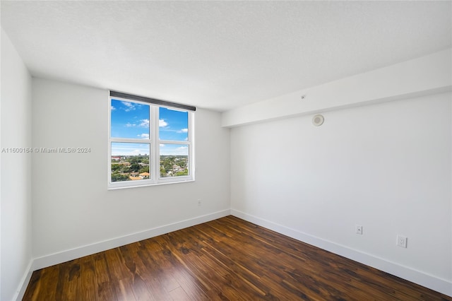 empty room featuring baseboards and dark wood-style flooring